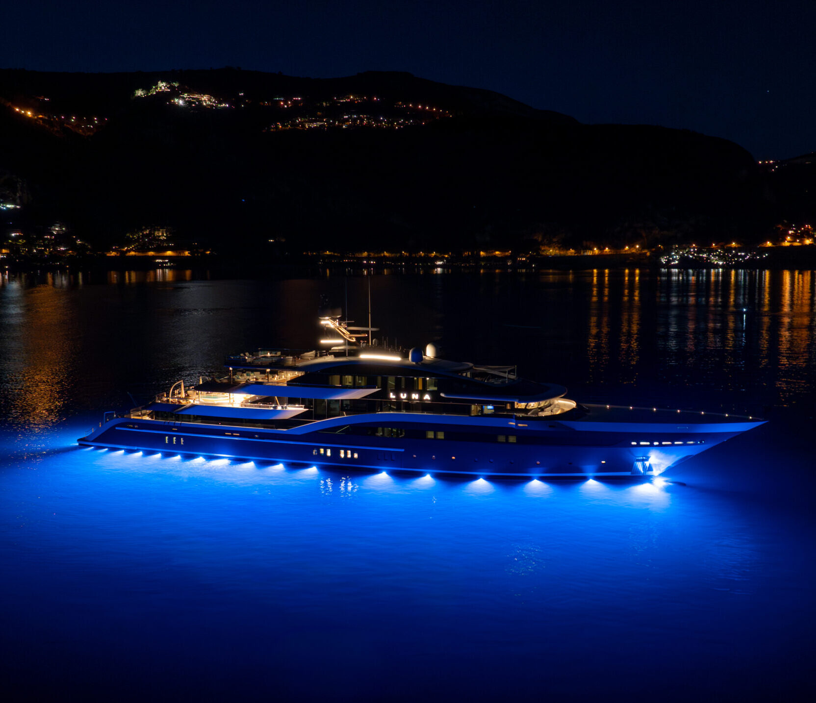 Luna at anchor at night, lit from below the waterline